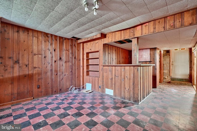 unfurnished room with bar and wooden walls