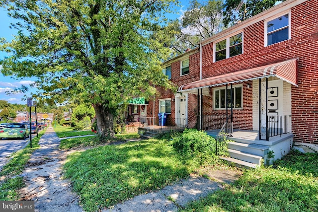 townhome / multi-family property with a front lawn and covered porch