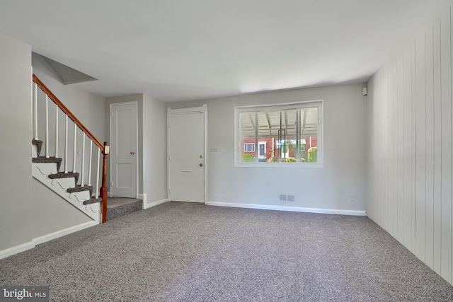 carpeted spare room featuring wood walls