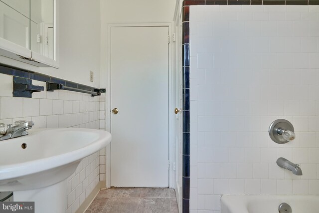 bathroom with tile patterned floors, sink, tile walls, and tiled shower / bath