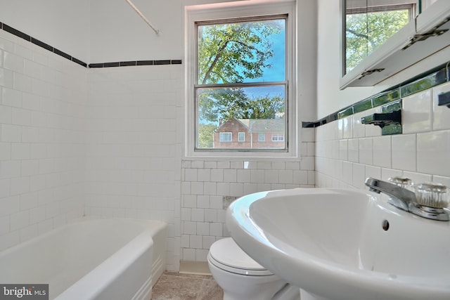 bathroom featuring toilet, a bathtub, sink, tile walls, and tile patterned flooring