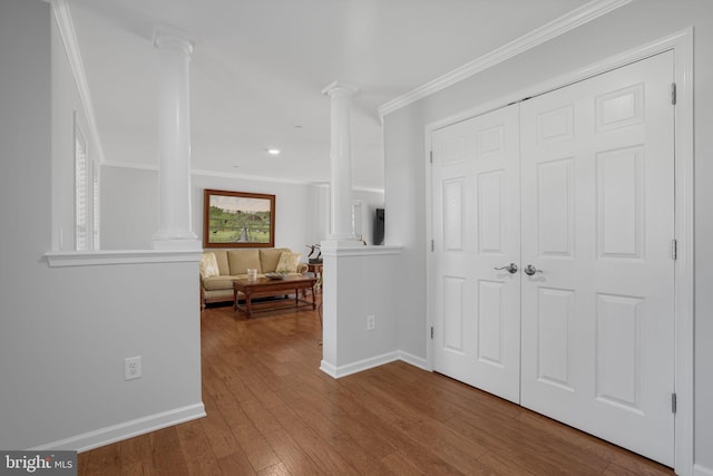 hallway featuring hardwood / wood-style flooring, crown molding, and decorative columns