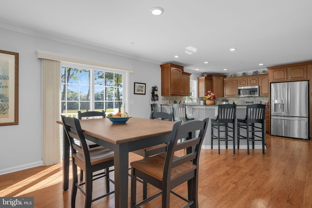 dining area featuring ornamental molding, sink, and light hardwood / wood-style floors