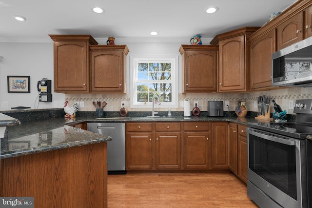 kitchen featuring light hardwood / wood-style flooring, ornamental molding, appliances with stainless steel finishes, and sink