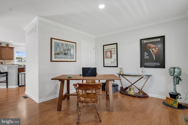 office space featuring ornamental molding, sink, and light hardwood / wood-style flooring