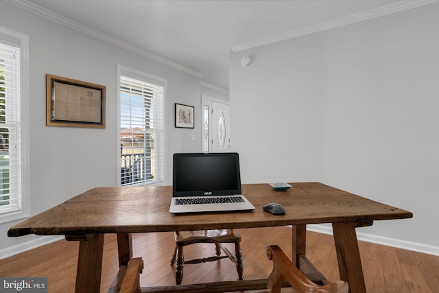 home office featuring wood-type flooring, ornamental molding, and a healthy amount of sunlight