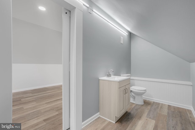 bathroom featuring lofted ceiling, hardwood / wood-style flooring, vanity, and toilet