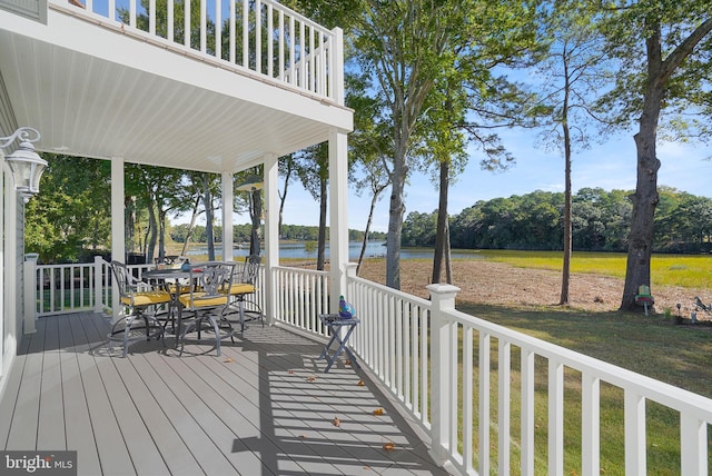 wooden terrace featuring a lawn and a water view