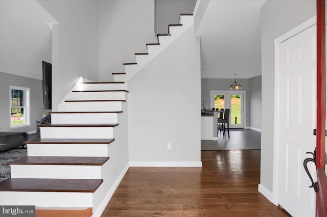 stairs featuring wood-type flooring and an inviting chandelier