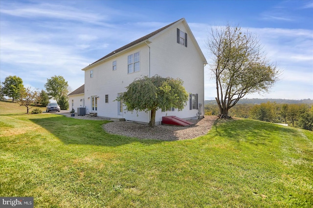 rear view of house featuring a lawn and central air condition unit