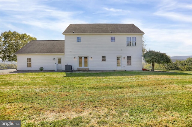 rear view of house featuring french doors, cooling unit, and a lawn