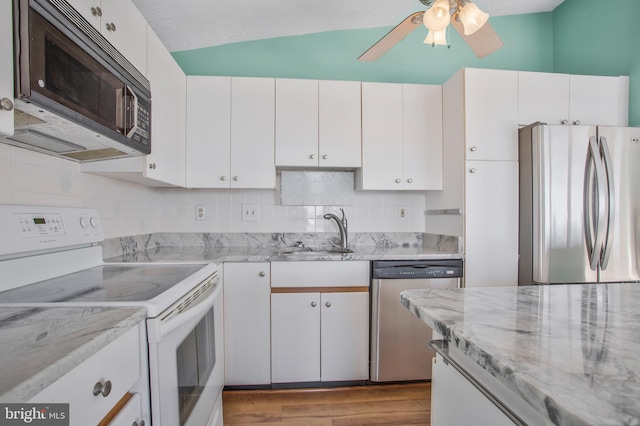 kitchen featuring lofted ceiling, appliances with stainless steel finishes, sink, and white cabinets