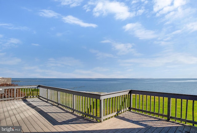 wooden terrace with a water view and a lawn