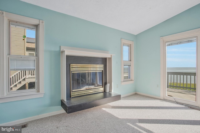 unfurnished living room with carpet, vaulted ceiling, and a textured ceiling