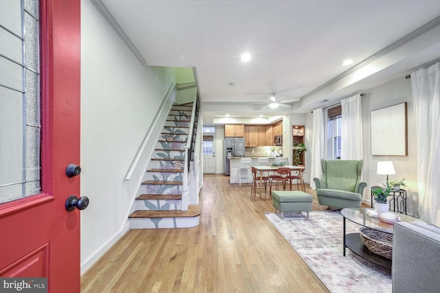 living room with light hardwood / wood-style floors, ceiling fan, and crown molding