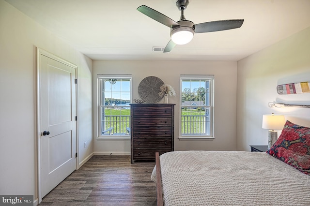 bedroom featuring ceiling fan, multiple windows, and dark hardwood / wood-style floors