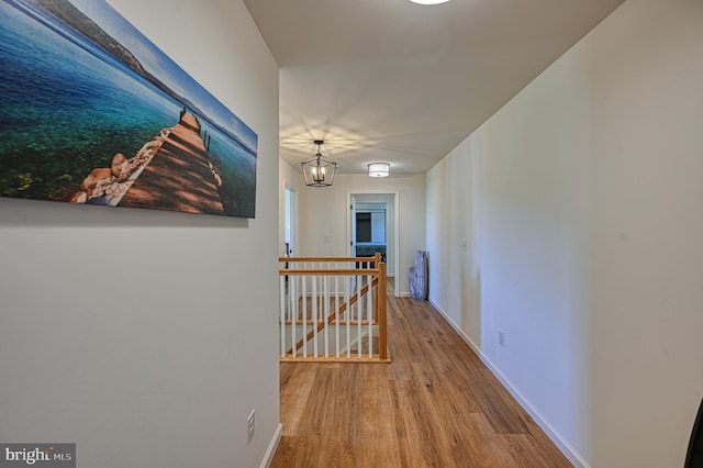 hallway with a notable chandelier and hardwood / wood-style flooring