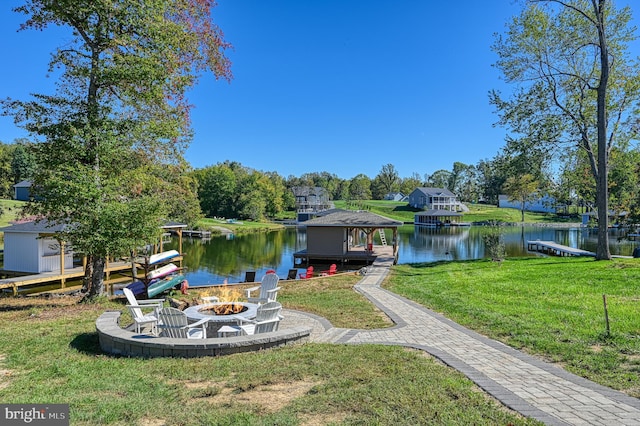 view of dock with a lawn, a water view, and a fire pit