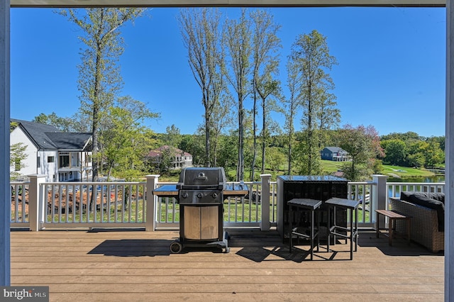 wooden terrace featuring area for grilling and a water view