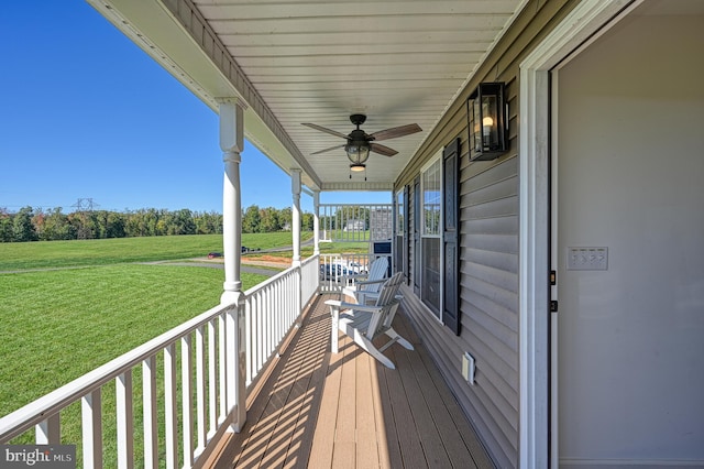 wooden terrace featuring covered porch, a lawn, and ceiling fan