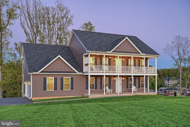 view of front of home with a balcony, a garage, and a lawn