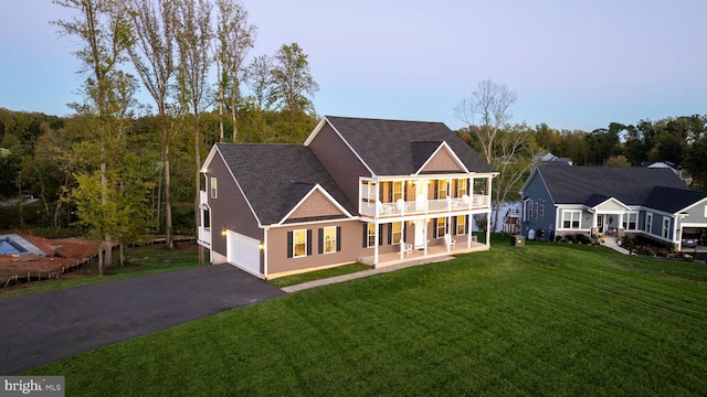 back of house with a balcony, a garage, and a lawn