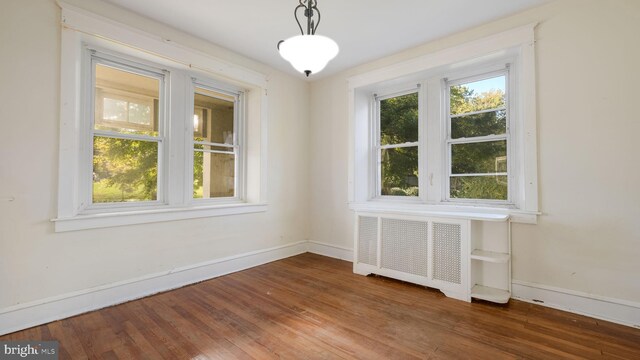 unfurnished dining area featuring radiator, dark hardwood / wood-style floors, and plenty of natural light