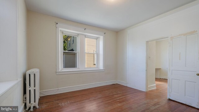 unfurnished bedroom featuring dark wood-type flooring and radiator heating unit