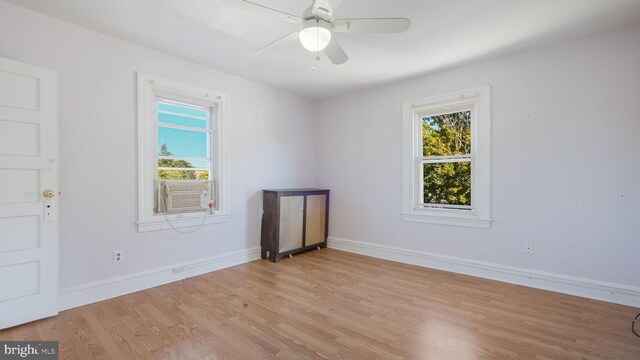 empty room with cooling unit, ceiling fan, and light hardwood / wood-style flooring