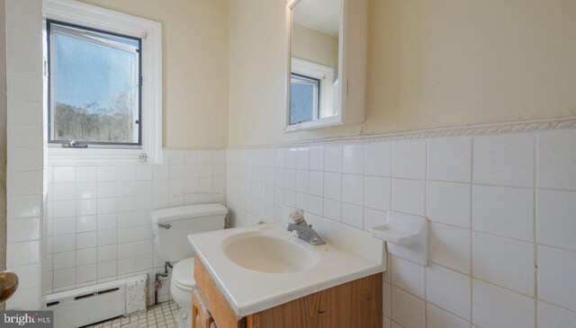 bathroom with vanity, a healthy amount of sunlight, a baseboard radiator, and tile walls