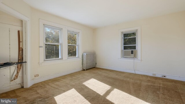 unfurnished room with radiator heating unit, cooling unit, and light carpet