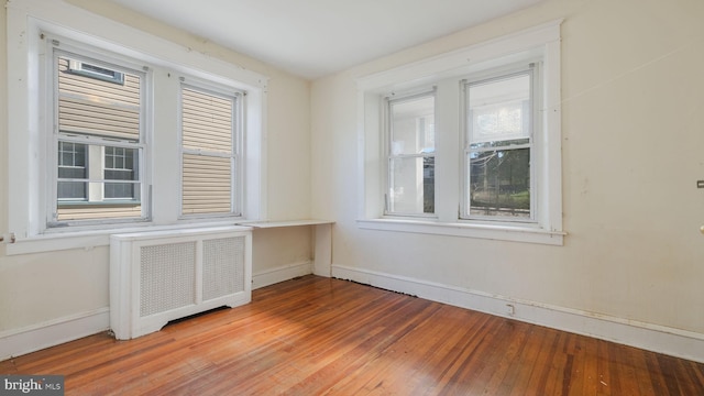 unfurnished room with hardwood / wood-style floors and radiator heating unit