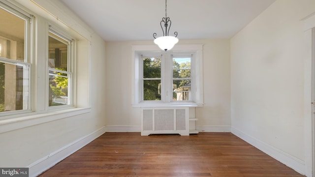 unfurnished dining area with radiator heating unit and dark hardwood / wood-style floors