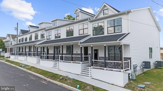 multi unit property with a shingled roof, a porch, and cooling unit