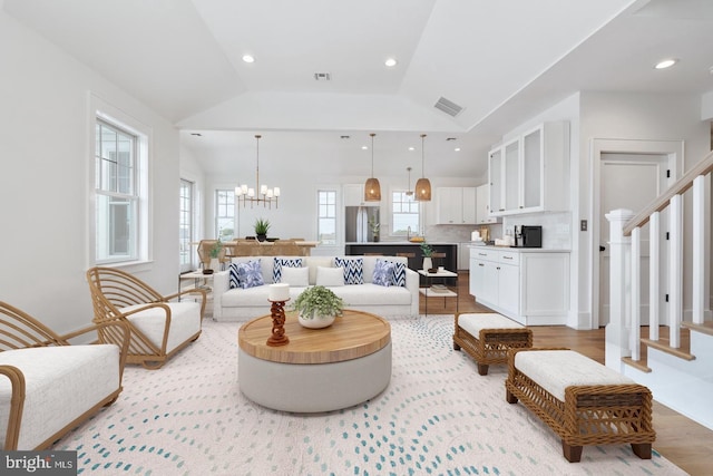 living room with vaulted ceiling, light wood-type flooring, and an inviting chandelier