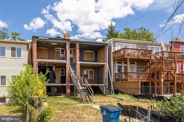 rear view of property featuring a deck and a lawn