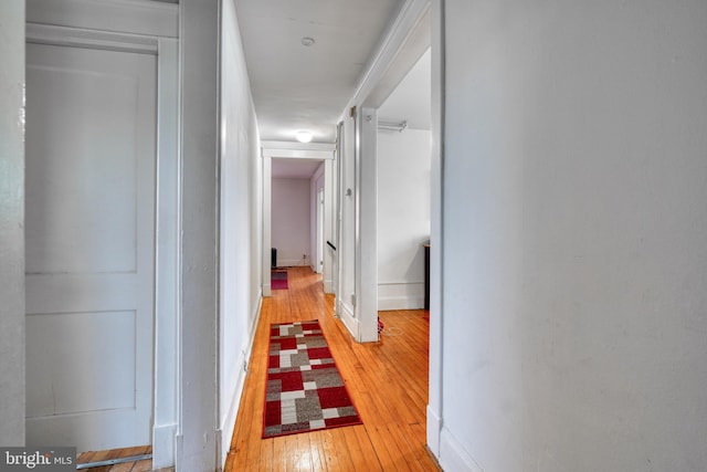 hall featuring light wood-type flooring and baseboards