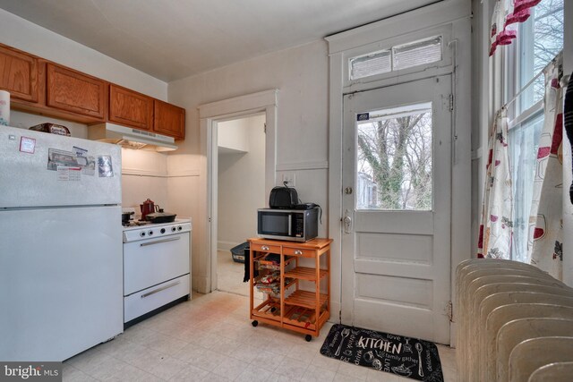 kitchen with brown cabinets, white appliances, radiator, and under cabinet range hood