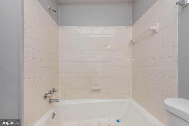 bathroom with toilet and tiled shower / bath