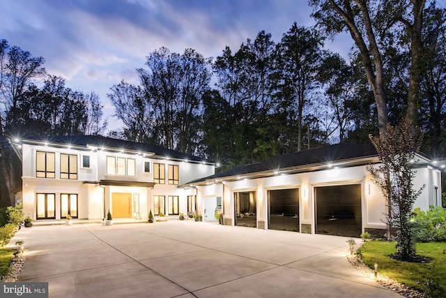 view of front facade featuring concrete driveway, an attached garage, a balcony, and stucco siding