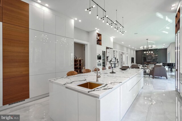 kitchen with white cabinets, marble finish floor, a sink, and modern cabinets