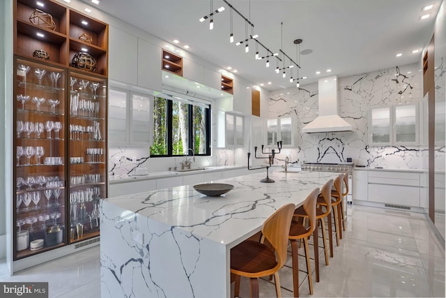 kitchen with sink, a spacious island, white cabinetry, pendant lighting, and custom exhaust hood