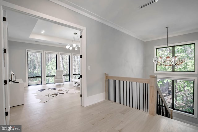 hall featuring ornamental molding, an inviting chandelier, and light wood-type flooring