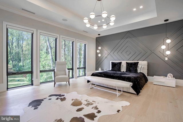 bedroom featuring a notable chandelier, a tray ceiling, and light wood-type flooring