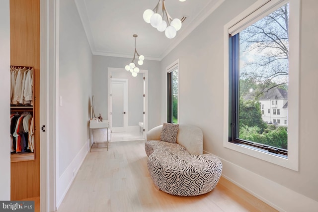 living area featuring crown molding, light wood-type flooring, a healthy amount of sunlight, and a chandelier