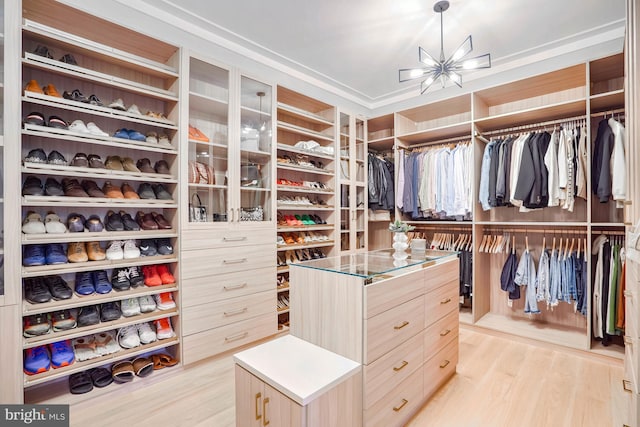 spacious closet featuring a notable chandelier and light wood-type flooring