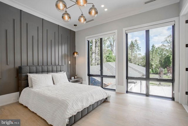 bedroom featuring ornamental molding, a chandelier, light hardwood / wood-style flooring, and access to outside