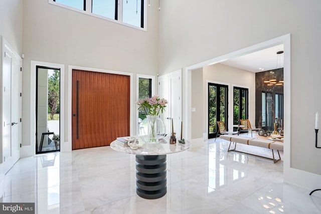 foyer featuring a wealth of natural light, a notable chandelier, and a towering ceiling