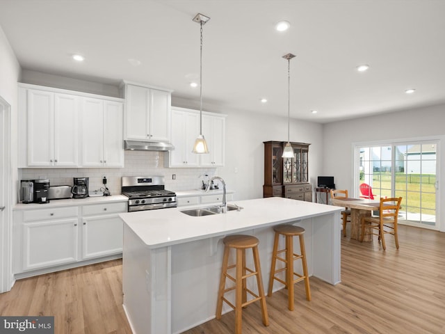 kitchen featuring white cabinets, sink, hanging light fixtures, and stainless steel range with gas cooktop