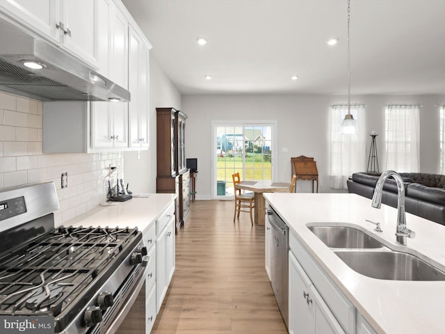 kitchen featuring pendant lighting, white cabinets, sink, light hardwood / wood-style flooring, and appliances with stainless steel finishes